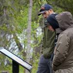 Attendees read informational displays while walking the trail during a reopening celebration for the Kbeq Cultural Heritage Interpretive Site near Cooper Landing, Alaska, on Friday, June 7, 2024. (Jake Dye/Peninsula Clarion)