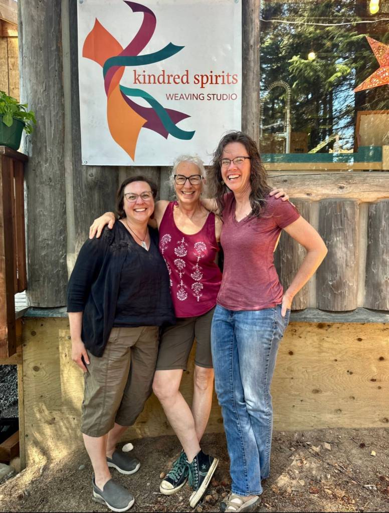 Kindred Spirits Lisa Talbott, Kyra Wagner and Bonita Banks pose on Sunday, June 16, 2024 in front of the Kindred Spirits Weaving Studio, a historic cabin in downtown Homer, Alaska, which has been converted into their working studio. Photo by Christina Whiting