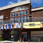 Pride flags adorn the upper balcony on Kachemak Bay Campus's Pioneer Hall during the Homer Pride Liberation Celebration held in the parking lot on Saturday, June 15, 2024, in Homer, Alaska. (Delcenia Cosman/Homer News)