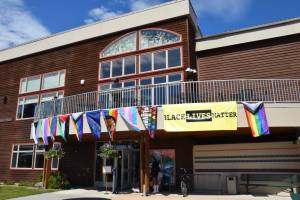 Pride flags adorn the upper balcony on Kachemak Bay Campus's Pioneer Hall during the Homer Pride Liberation Celebration held in the parking lot on Saturday, June 15, 2024, in Homer, Alaska. (Delcenia Cosman/Homer News)