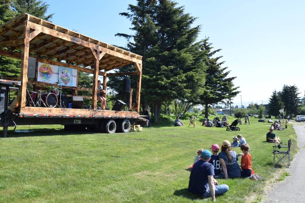 Community members camp out on the grass by Hazel Avenue as Rachel Witman performs on the guitar at the 2nd annual Summer Solstice Fair on Saturday, June 22, 2024, in Homer, Alaska. (Delcenia Cosman/Homer News)