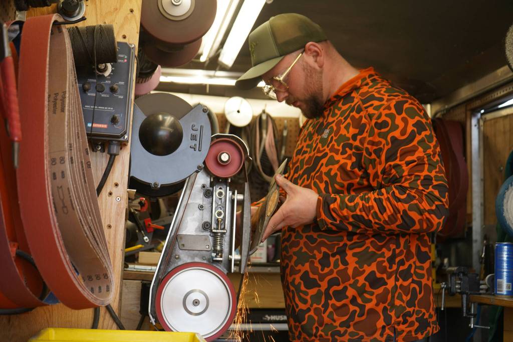 Sparks glitter away as Grey Wilson, of Wilsons Proper Edge, sharpens an ax at Soldotna Creek Park in Soldotna, Alaska, on Wednesday, June 19, 2024. (Jake Dye/Peninsula Clarion)