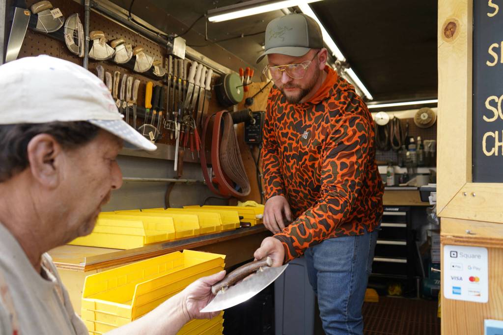 Grey Wilson, of Wilsons Proper Edge, returns a freshly sharpened ulu to its owner at Soldotna Creek Park in Soldotna, Alaska, on Wednesday, June 19, 2024. (Jake Dye/Peninsula Clarion)