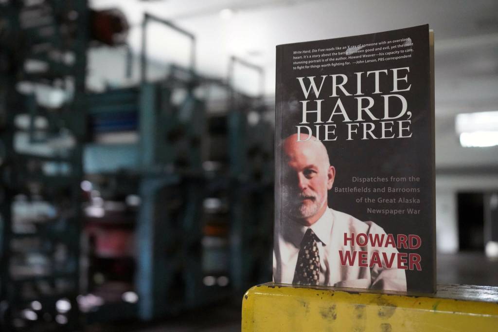 A copy of Howard Weavers memoir Write Hard, Die Free rests on an ink-splotched guard rail in front of the Peninsula Clarions defunct Goss Suburban printing press in Kenai, Alaska, on Thursday, June 20, 2024. (Jake Dye/Peninsula Clarion)
