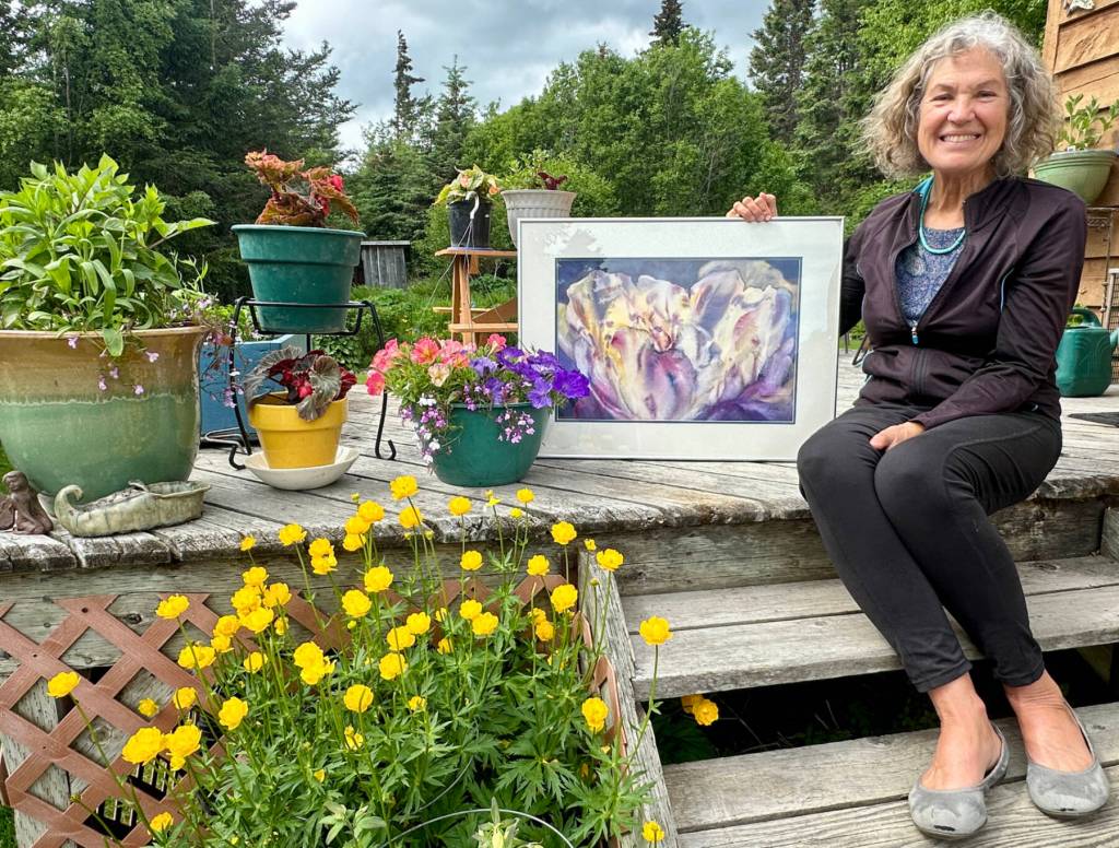 Jan Peyton poses with Open Heart, a watercolor painting she began in 2003 and recently completed, on Wednesday, June 26, 2024, at her home in Homer, Alaska. Open Heart will be on display in her solo exhibit, Ode to Fireweed, in July at Fireweed Gallery. Photo by Christina Whiting