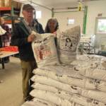 Al and Grace Poindexter pose with the Fishy Peat potting soil in the Anchor Point Greenhouse on July 8, 2024. (Emilie Springer/ Homer News)