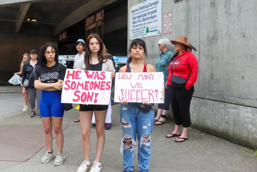 From left to right: Savannah Brohard, Marley Webster and Ariilana Shodda-Lee stand with signs outside the Juneau Public Library on Sunday. (Jasz Garrett / Juneau Empire)