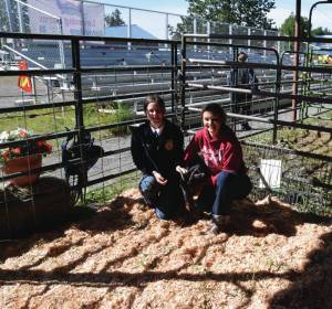 Morgan Carlson-Kelly and Jolie Webb, members of the Ninilchik FFA, pose at the petting zoo at the Ninilchik Fair on Aug. 9 in Ninilchik. Emilie Springer/ Homer News