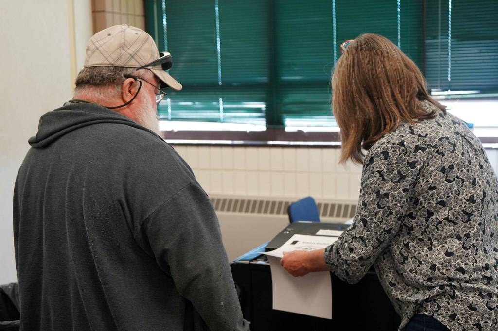 A poll worker helps a voter cast their ballot at the Soldotna Regional Sports Complex in Soldotna, Alaska, during the Alaska Primary Election Day on Tuesday, Aug. 20, 2024. (Jake Dye/Peninsula Clarion)
