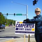 Diane Bush waves signs for Rep. Ben Carpenter, R-Nikiski, on the side of the Sterling Highway in Soldotna, Alaska, during the Alaska Primary Election Day on Tuesday, Aug. 20, 2024. (Jake Dye/Peninsula Clarion)