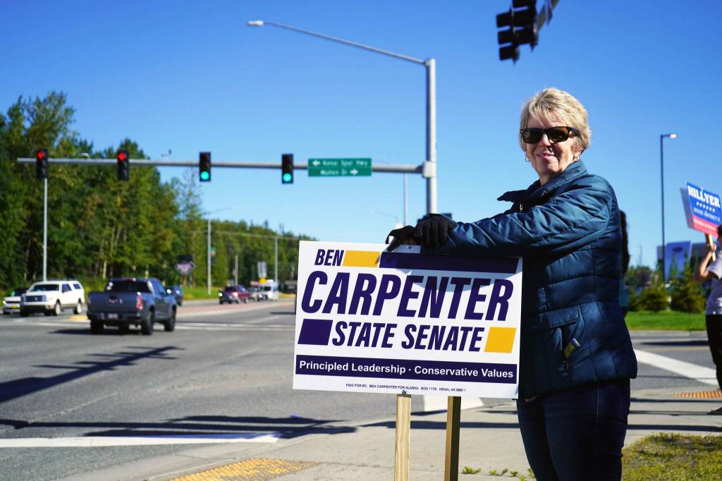 Diane Bush waves signs for Rep. Ben Carpenter, R-Nikiski, on the side of the Sterling Highway in Soldotna, Alaska, during the Alaska Primary Election Day on Tuesday, Aug. 20, 2024. (Jake Dye/Peninsula Clarion)