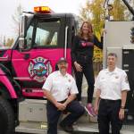 Jess Gutzwiler, director of community outreach for Aurora Integrated Oncology Foundation, stands with Central Emergency Services Fire Marshal Charles Roney and Chief Roy Browning during an unveiling of Miss Rosey, a pink fire engine dedicated to raising awareness about cancer prevention and screening, at Central Peninsula Hospital in Soldotna, Alaska, on Saturday, Sept. 28, 2024. (Jake Dye/Peninsula Clarion)