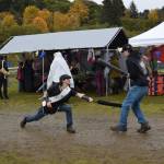 Two fairgoers battle it out with foam swords opposite the sparring arena at Ye Olde Harvest Festival at Karen Hornaday Park on Saturday, Oct. 5, 2024, in Homer, Alaska. (Delcenia Cosman/Homer News)