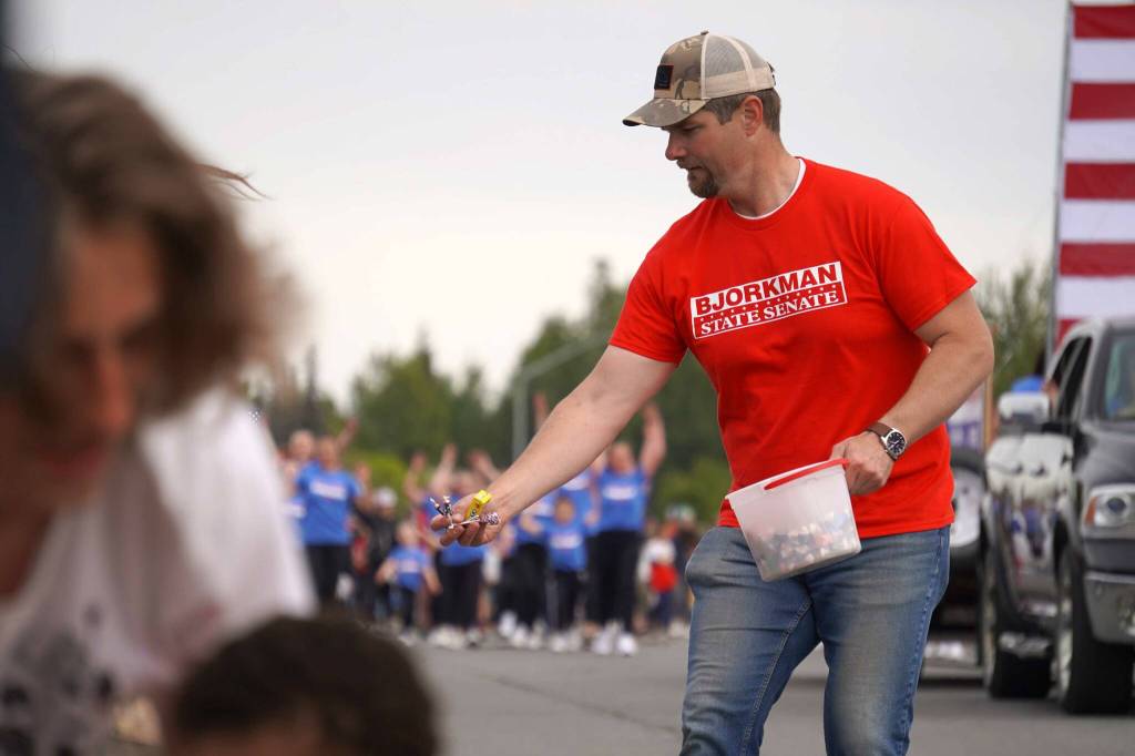 Sen. Jesse Bjorkman, R-Nikiski, hands Tootsie Rolls and other candy to children on South Willow Street in Kenai, Alaska, during the Fourth of July Parade on Thursday, July 4, 2024. (Jake Dye/Peninsula Clarion)