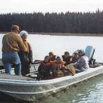 Photo courtesy of the Fair Family Collection
Jane Fair (standing, wearing white hat) receives help with her life jacket from Ron Hauswald prior to the Fair and Hauswald families embarking on an August 1970 cruise with Phil Ames on Tustumena Lake. Although conditions were favorable at first, the group soon encountered a storm that forced them ashore.
