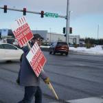 Jesse Bjorkman crosses the Sterling Highway while carrying campaign signs in Soldotna, Alaska, on Tuesday, Nov. 5, 2024. (Jake Dye/Peninsula Clarion)