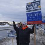 Cindy Roque waves signs for Ben Carpenter and John Hillyer along the Kenai Spur Highway in Kenai, Alaska, on Tuesday, Nov. 5, 2024. (Jake Dye/Peninsula Clarion)