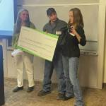 Homer Foundation Executive Director Stacey Schultz, left, receives from Jules and Dawn Ravin an honorary $1.2 million check to support youth in the community at the foundations annual board meeting at the Kachemak Bay Campus , Nov. 14. (Photo by Emilie Springer/Homer News)