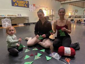 Homer Nutcracker dancers Ella Gustufson and Sofia Loboy help create Christmas tree gift tags for the 2024 Homer Share the Spirit in the Homer High School green room during Nutcracker rehearsal last weekend. They are joined by one of the Nutcrackers small participants. (Emilie Springer/Homer News)