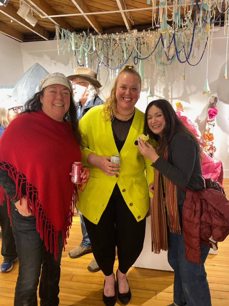 Artist Abigail Kokai (center) with friends Rachael Brennan (left) and Karianna Ford (right) attend the opening of her December mixed media exhibit, centered around her fictional character Aelon Funk and his extraterrestrial travels, at Bunnell Street Arts Center on Friday, Dec. 6, 2024, in Homer, Alaska. Photo provided by Abigail Kokai