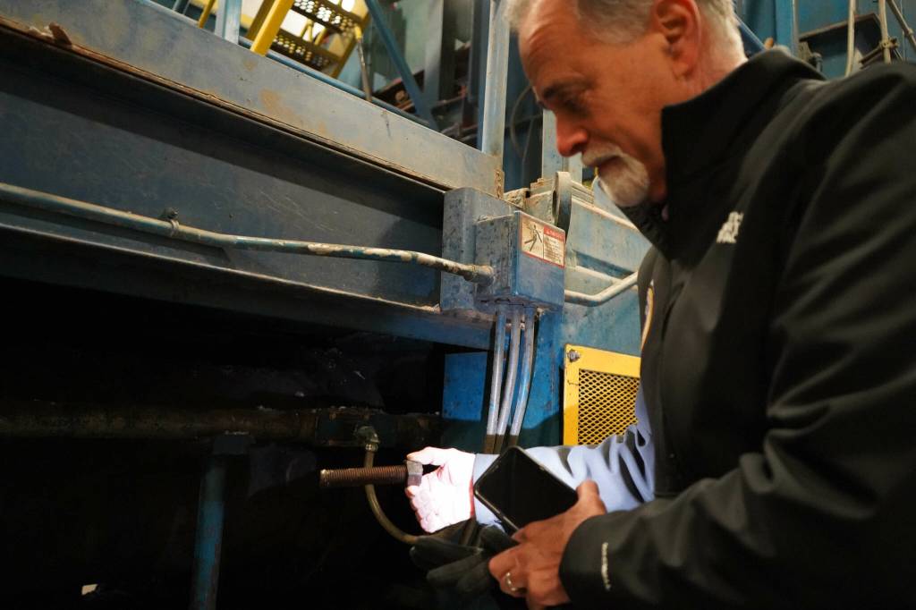 Kenai Peninsula Borough Mayor Peter Micciche holds one of the large bolts that formerly connected the baler ram to the larger machine at the Central Peninsula Landfill in Soldotna, Alaska, on Thursday, Jan. 16, 2025. (Jake Dye/Peninsula Clarion)
