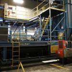 A large baler fills a building at the Central Peninsula Landfill in Soldotna, Alaska, on Thursday, Jan. 16, 2025. Before the ram attached to the bottom left was severed from the machine in a December failure, material was carried by a conveyor belt to the tower on the right and compressed into cubes. (Jake Dye/Peninsula Clarion)