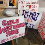 Signs from the Homer Womens March on Saturday, Jan. 18, 2025, are displayed during the afterparty at Kachemak Bay Campus in Homer, Alaska. (Delcenia Cosman/Homer News)