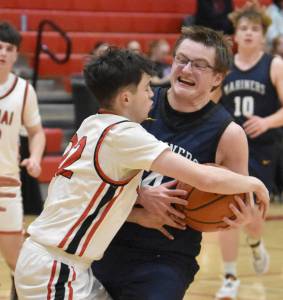 Homers Einar Pederson drives on Kenai Centrals Ben Harris on Tuesday, Jan. 21, 2025, at Kenai Central High School in Kenai, Alaska. (Photo by Jeff Helminiak/Peninsula Clarion)