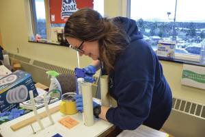 Amy Woodruff demonstrates an example of how to properly caulk a seam at the Homer Energy Fair on Saturday, Jan. 25. She said she was inspired to learn DIY home efficiency improvements when she became a homeowner. (Chloe Pleznac/Homer News)