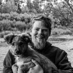 Homer photographer Andrew Tomey poses with his dog, Gila, at the Anchor River in 2022. Photo courtesy of Zeb Perkins