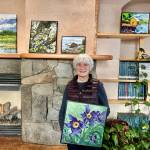 Diane Spence-Chorman poses on Jan. 30, 2025, with her oil painting, Pasque Flowers, currently on display with 12 other original works through March in the Homer Public Librarys Fireplace Lounge in Homer, Alaska. Photo by Christina Whiting