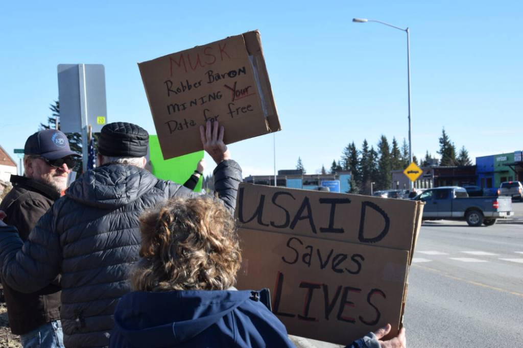 Community members hold up protest signs during the Stand for Democracy Rally on International Womens Day, March 8, 2025, at WKFL Park in Homer, Alaska. (Chloe Pleznac/Homer News)