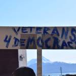 A community member holds up a protest sign at the Stand for Democracy Rally on International Womens Day, March 8, 2025 at WKFL Park in Homer, Alaska. (Chloe Pleznac/Homer News)