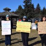 Community members hold up protest signs during the Stand for Democracy Rally on International Womens Day, March 8, 2025, at WKFL Park in Homer, Alaska. (Chloe Pleznac/Homer News)