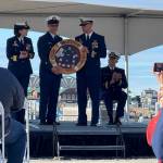 The commissioning pennant is presented to Lt. Ross Markham by the youngest member of the crew while Rear Admiral Megan Dean applauds on Friday, March 21, 2025, on Freight Dock Road on the Homer Spit. (Chloe Pleznac/Homer News)