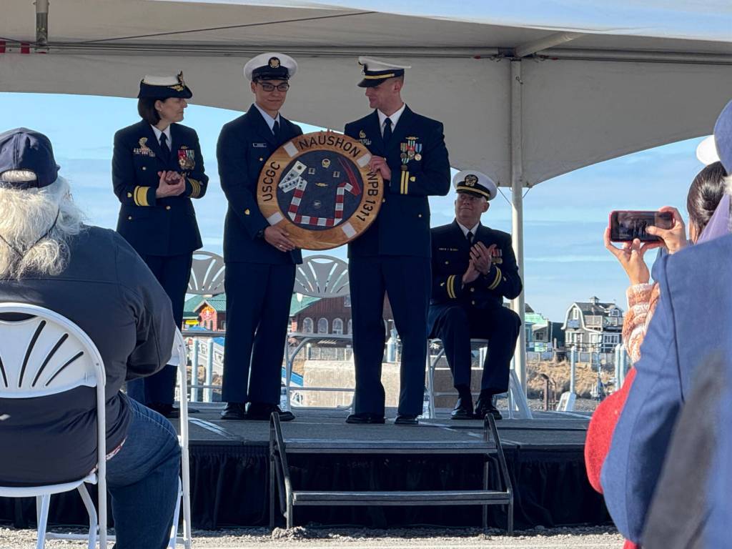 The commissioning pennant is presented to Lt. Ross Markham by the youngest member of the crew while Rear Admiral Megan Dean applauds on Friday, March 21, 2025, on Freight Dock Road on the Homer Spit. (Chloe Pleznac/Homer News)