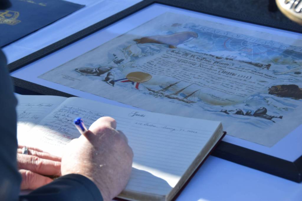 An attendee of the decommissioning ceremony signs the vessels guest book on Friday, March 21, 2025, on Freight Dock Road on the Homer Spit in Homer, Alaska. (Chloe Pleznac/Homer News)