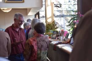 Community members peruse the silent auction items while conversing during the annual Celebration of Lifelong Learning event at the Homer Public Library on Saturday, March 29, 2025. (Chloe Pleznac/Homer News)