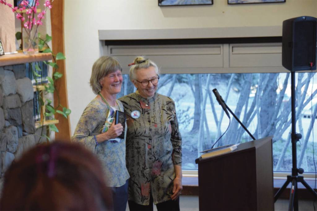 Awardee Carol Comfort-Waldorf, left, and Friends of the Homer Library President Joy Steward stand in front of the gathered crowd during the annual Celebration of Lifelong Learning event at the Homer Public Library on Saturday, March 29, 2025. Steward presented the award to Comfort-Waldorf. (Chloe Pleznac/Homer News)