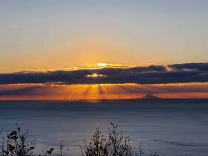 The setting sun over Kachemak Bay highlights Mount Augustine in the distance on Thursday, Oct. 17, 2024, in Homer, Alaska. (Delcenia Cosman/Homer News)