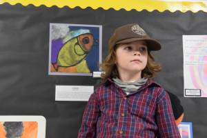 Student Raiden Dailey poses with his art on display at Paul Banks Elementary School during the annual Arts Extravaganza on Friday, April 4. (Chloe Pleznac/Homer News)