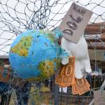 Jane Dunns protest art stands beside the crowd gathered during the nationwide Hands Off! protest on Saturday, April 5 at WKFL Park in Homer, Alaska. (Chloe Pleznac/Homer News)