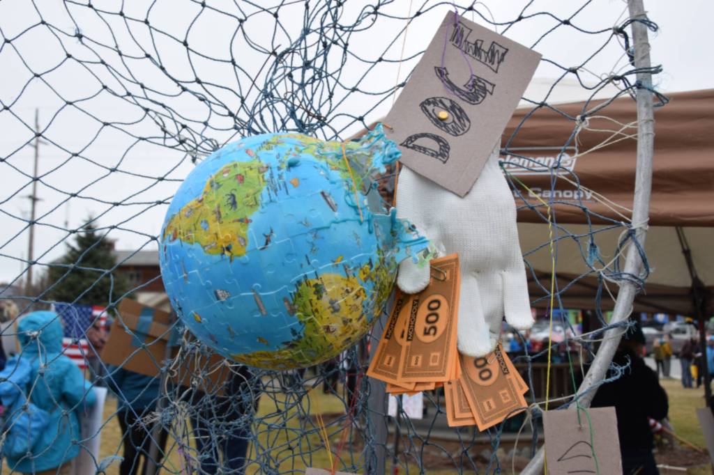 Jane Dunns protest art stands beside the crowd gathered during the nationwide Hands Off! protest on Saturday, April 5 at WKFL Park in Homer, Alaska. (Chloe Pleznac/Homer News)