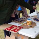 Protesters create signs during the nationwide Hands Off! protest on Saturday, April 5 at WKFL Park in Homer, Alaska. (Chloe Pleznac/Homer News)