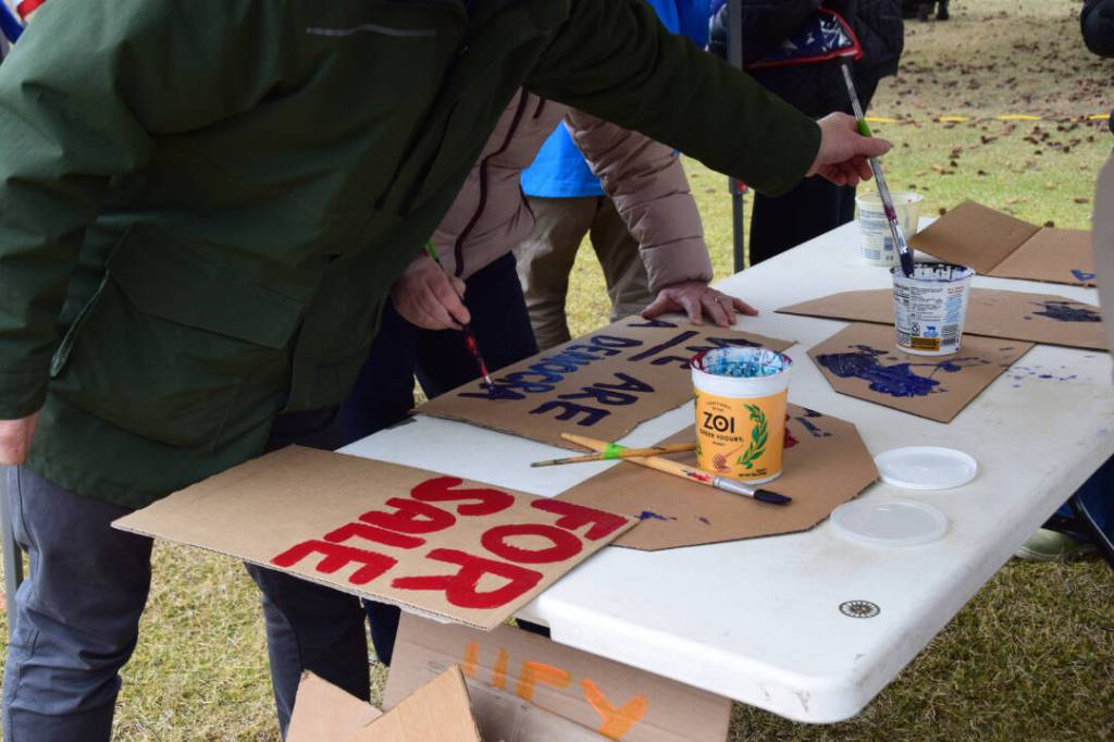 Protesters create signs during the nationwide Hands Off! protest on Saturday, April 5 at WKFL Park in Homer, Alaska. (Chloe Pleznac/Homer News)