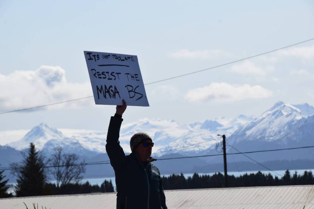 A man stands with a protest sign on Saturday, April 19 at WKFL Park during the Sustained Resistance, Makes a Difference Rally. (Chloe Pleznac/Homer News)