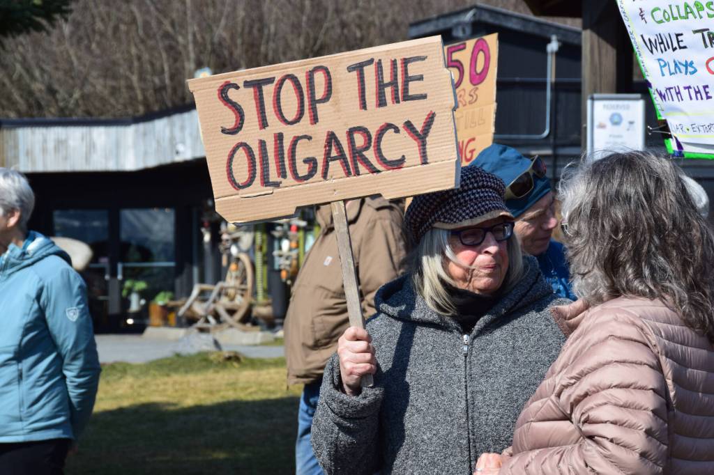 Artist Mavis Muller holds up a sign that reads STOP THE OLIGARCY on Saturday, April 19 at WKFL Park during the Sustained Resistence, Makes a Difference Rally. (Chloe Pleznac/Homer News)