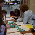 West Homer Elementary school teacher Mrs. Hanks works with kids on crafting All About Me cubes on Friday, May 2, 2025, in Homer, Alaska. The cubes are a way for kids to explore expressing things like their hobbies, family and friendships, and favorite foods, colors, and more. (Chloe Pleznac/Homer News)