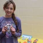 Margaret Gricius stands holding one of her ceramic art pieces, showcased during the annual Arts Extravaganza at West Homer Elementary School on Friday, May 2, 2025, in Homer, Alaska. (Chloe Pleznac/Homer News)