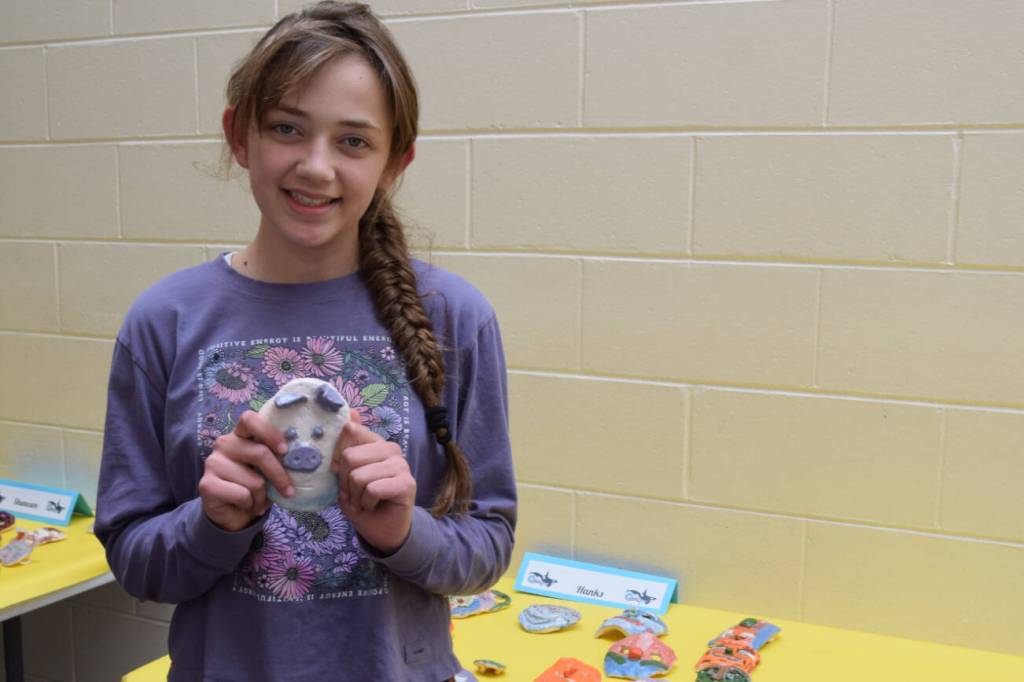 Margaret Gricius stands holding one of her ceramic art pieces, showcased during the annual Arts Extravaganza at West Homer Elementary School on Friday, May 2, 2025, in Homer, Alaska. (Chloe Pleznac/Homer News)